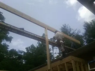 Carpenter setting a ridge beam over a new addition frame — Ice Dam Removal by Roofing Brothers in Sweeden