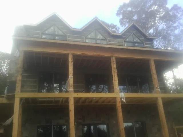 Dormers and porch framing on a large log home under construction — Roof Coating work by our crew in Sweeden