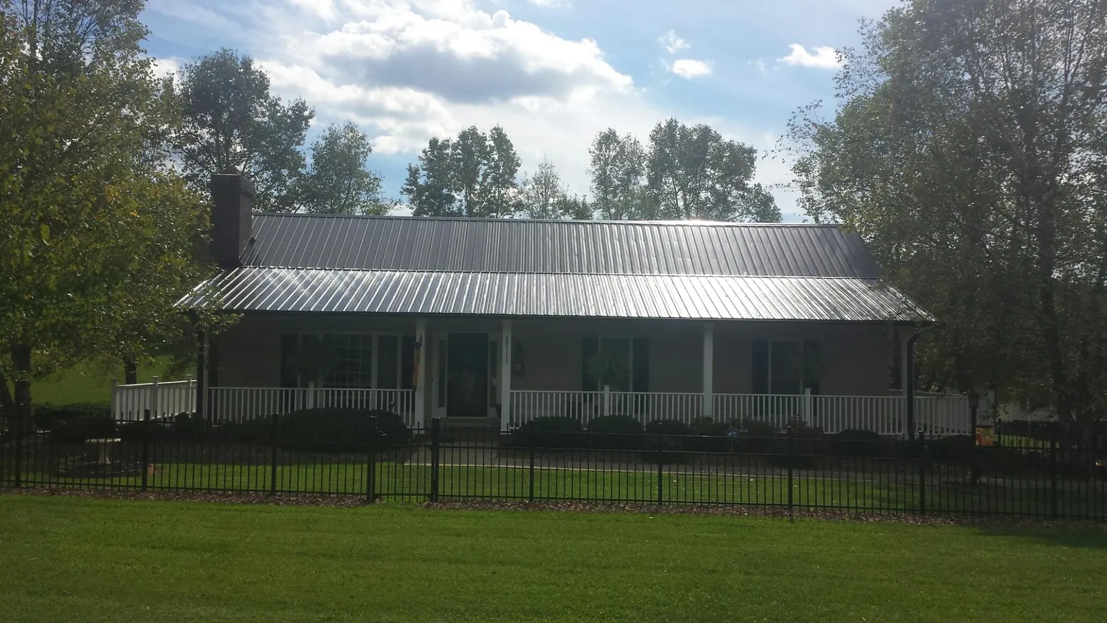 Gray metal roof on a brick ranch with a full width front porch — Gutter Guard Installation work by our crew in Sweeden