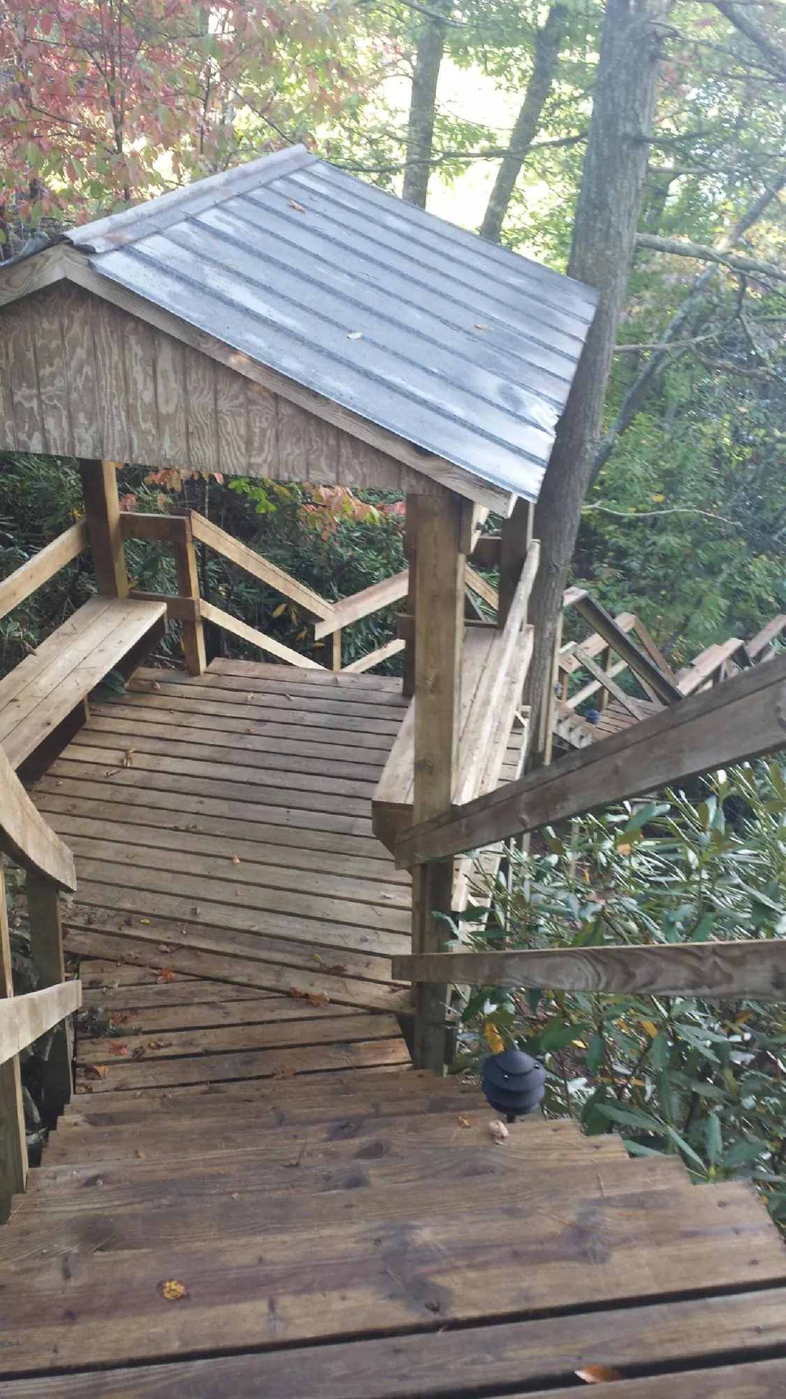 Metal roofed shelter over wooden steps on a wooded walkway — Skylight Repair & Installation work by our crew in Sweeden